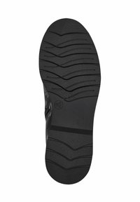 Suela de zapato negra con una superficie texturizada, que presenta estrías horizontales y una punta redondeada. Material de goma duradero para un mejor agarre.