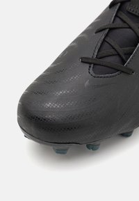 Black soccer cleat with textured synthetic upper, featuring a smooth finish, elongated toe, and black laces. Cleat studs in turquoise.