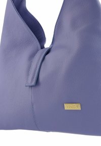 Violette Lederhandtasche mit strukturiertem Finish. Sie verfügt über eine goldene Logo-Plakette und ein modernes, strukturiertes Design mit einer lässigen Silhouette.