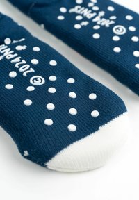 Calze blu navy con punti antiscivolo bianchi e un accento bianco sulle punte. Realizzate in un materiale a maglia testurizzato con il nome del marchio visibile.