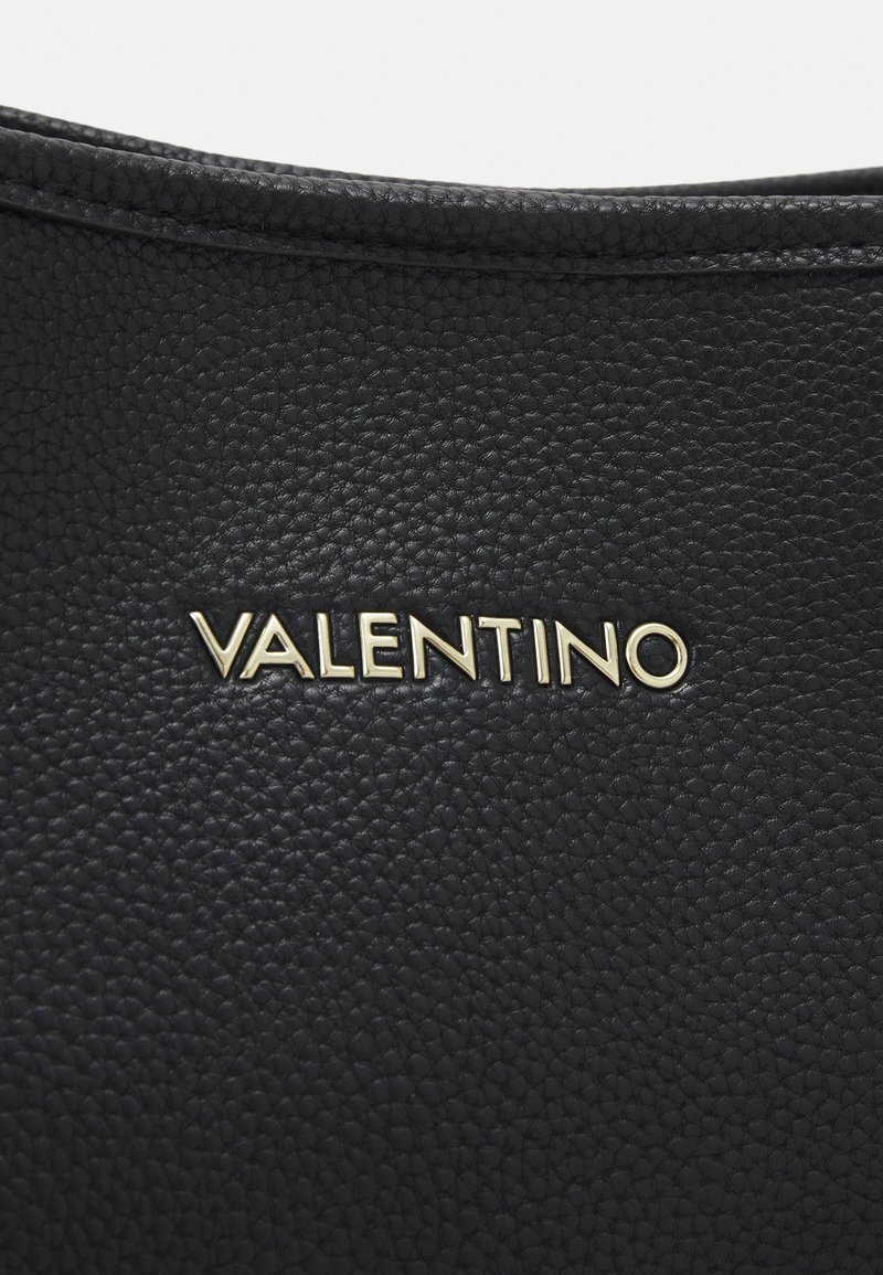 Schwarze Lederhandtasche mit strukturierter Oberfläche, mit dem goldenen "VALENTINO"-Logo, das prominent in der Mitte platziert ist.