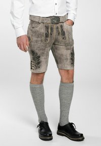 Grijze leren shorts met geborduurde bloemenpatronen, gele stiksel, zijzakken en decoratieve knopen. Gecombineerd met grijze kniesokken en zwarte schoenen.