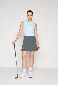 Lyseblå ermeløs polo med teksturert mønster og tre knapper, kombinert med en mørkegrå golfskjørt med en logo på kanten.