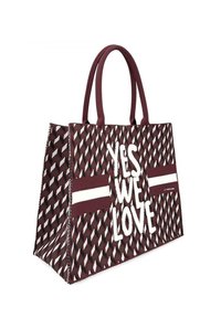 Borsa a spalla color marrone rossiccio realizzata in tessuto intrecciato, con un motivo geometrico, strisce bianche a contrasto e il testo "SÌ, CI PIACE" in una tipografia in grassetto.