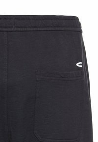 Sorte joggers i bomuldsblanding har en justerbar taljevadded, sidelommer og et broderet logo på bagsiden nær taljen.