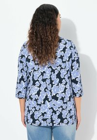 Kukkakuvioinen paita, jossa on kolmennesosa hihasta, tummansinisellä pohjalla ja vaaleansinisiä kukkakuvioita. Ilmava kangas ja rento malli.