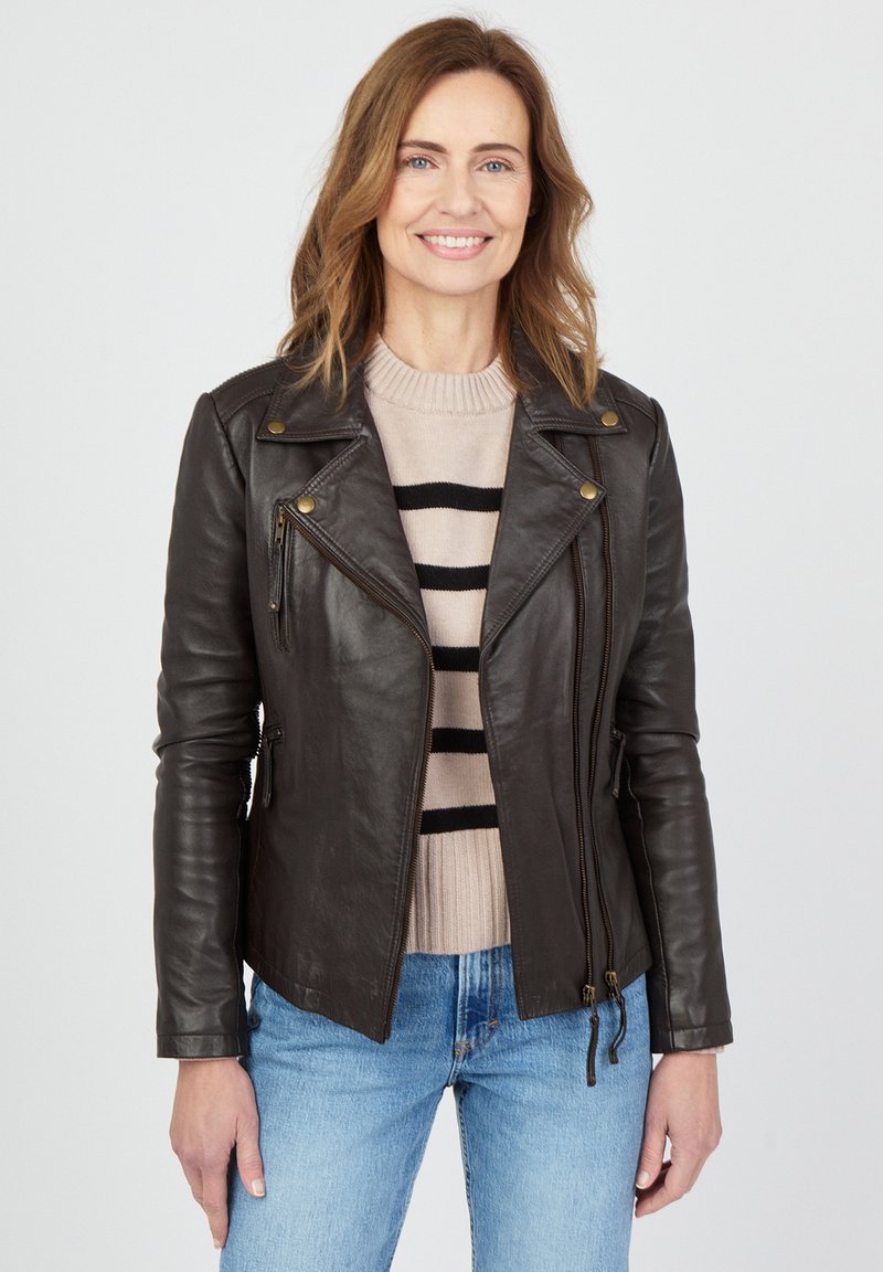 Ruskea nahkainen moottoripyöräntakki, jossa on vetoketjulliset taskut ja napit, päällä vaaleansävyinen raidallinen neule ja siniset farkut. Sujuva pinta.