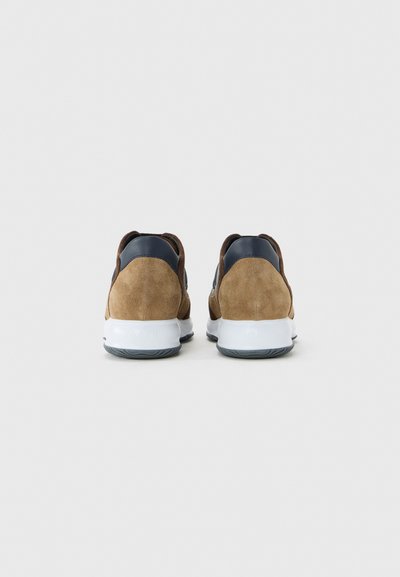 Pair of brown suede sneakers with white soles and dark blue heel accents, shown from the back on a light grey background.