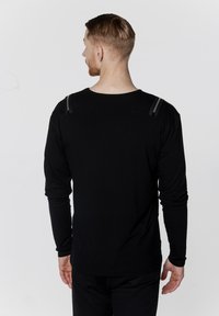 Czarna koszula z długim rękawem, okrągłym dekoltem, z szarymi akcentami na ramionach. Materiał wydaje się być miękki i lekko dopasowany w talii.