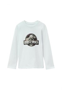 Biała koszula z długim rękawem z dużym logo Jurassic World i grafiką dinozaura, na okrągłym czarnym i szarym tle.