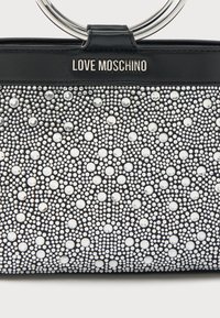 Μαύρη τσάντα χειρός από ύφασμα που φαίνεται σαν δέρμα, διακοσμημένη με ασημένιες καρφίτσες και στρας, με κυκλικό μεταλλικό χερούλι και λογότυπο "LOVE MOSCHINO".