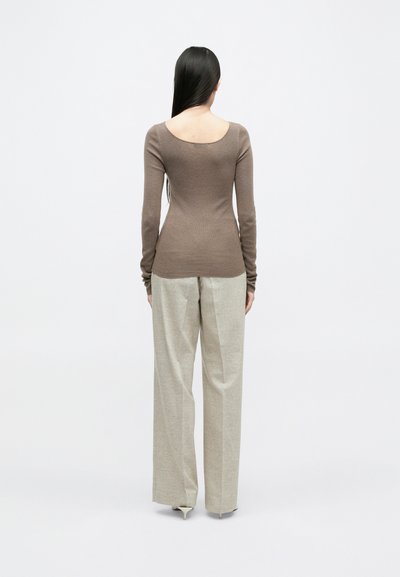 Brūns pieguļošs garām piedurknēm tops ar apaļu muguru, savienots ar gaišiem augstās jostasvietas platām biksēm, gluda tekstūra un minimāls dizains.