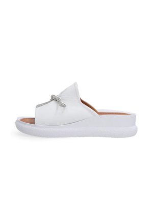 White slip-on sandal with a textured leather upper featuring a decorative rhinestone accent, and a cushioned white rubber sole.