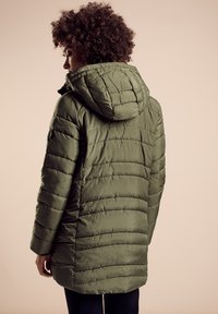 Olivgrön pufferjacka med huva, med vadderat mönster, texturerad yta och en längd som sträcker sig till midjan.