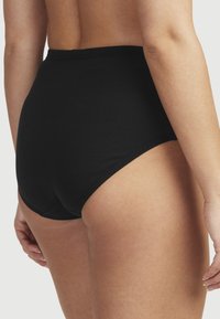 Höga svarta ribbade trosor med en slät midjeband, mjuk textur och åtsittande passform, med en sömlös design vid benöppningarna.