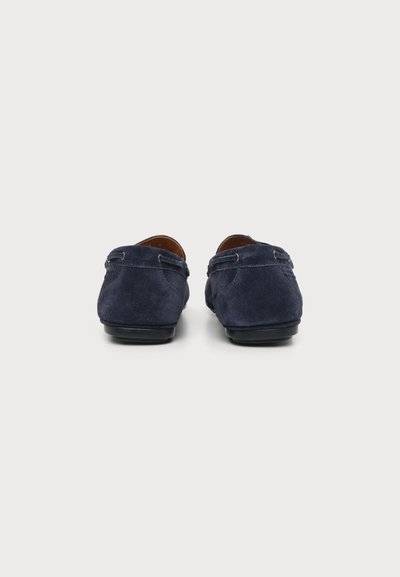 Paire de mocassins en daim bleu foncé vus de dos sur fond blanc.