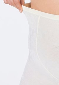 Beżowe shapewear o wysokim stanie z kwiatowymi wzorami, gładką fakturą i elastycznym pasem, podciągane ręką.