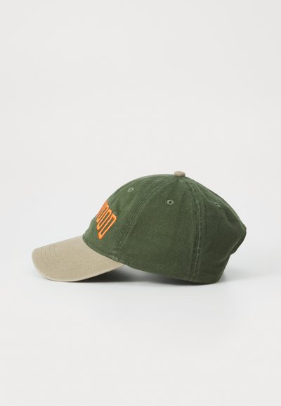 Grønn caps med brunt skygge, med oransje broderi på fronten. Laget av stoff med teksturert finish og rund form.