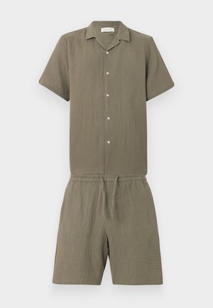 Combinaison courte à manches courtes de couleur olive avec boutons, col, taille élastique, cordon de serrage et tissu texturé.