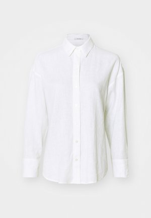 Chemise en lin blanche avec un col classique, des manches longues et une fermeture à boutons. Présente une coupe décontractée et une texture subtile sur l'ensemble.