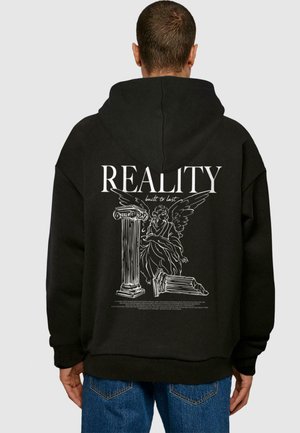 Juoda kapučinė striukė su dideliu baltu piešiniu ant nugaros, vaizduojančiu angelą šalia kolonos, su tekstu "REALITY built to last".