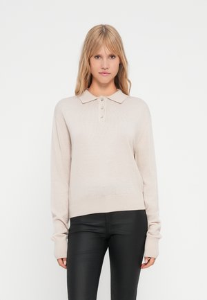 Pull en maille beige avec col polo, patte de boutonnage à quatre boutons et manches longues. Texture douce avec ourlet et poignets côtelés.