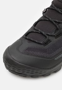 Chaussure de randonnée noire avec un dessus synthétique texturé, des accents en mesh et une semelle en caoutchouc robuste dotée de profonds crampons pour une meilleure adhérence.