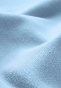 Tissu en coton bleu clair avec une texture lisse, présentant de légères élasticités et des motifs de tissage fins, créant une surface douce et uniforme.