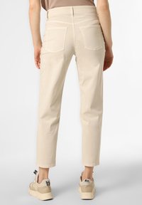 Pohodlné béžové bavlněné kalhoty volného střihu s mírně zkrácenou délkou, s kapsami na zadní straně a bezšvovým pasem, doplněné o béžové tenisky.