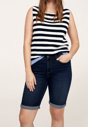 Top sin mangas a rayas en azul marino y blanco, combinado con pantalones cortos de mezclilla oscura con dobladillos enrollados y un diseño ajustado.