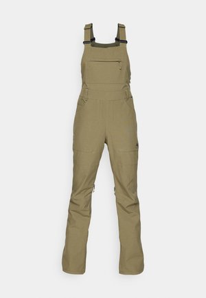Salopette verte olive en tissu résistant, dotée de bretelles réglables, d'une poche zippée à l'avant et de deux poches latérales. Design moderne et fonctionnel.
