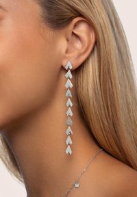 Silberne geometrische Ohrringe mit einem kaskadierenden Design aus verbundenen, alternierenden Chevron-Formen. Polierte Oberfläche, leicht und elongated.