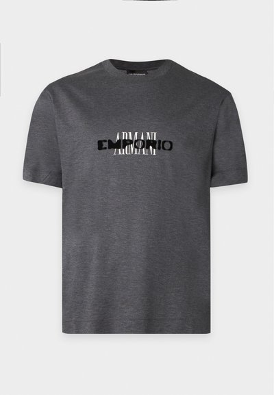 T-shirt gris foncé à manches courtes avec un texte blanc et noir superposé indiquant "ARMANI EMPORIO" sur la poitrine.
