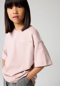 Vaaleanpunainen lyhythihainen t-paita, jossa on rento istuvuus. Varustettu brodeeratulla "ALLSAINTS" -logolla. Yhdistetty harmaisiin, teksturoituihin housuihin.