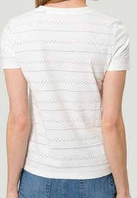 Hvid t-shirt med korte ærmer, der har teksturerede vandrette striber med små udsnit. Klassisk pasform med en rund halsudskæring og glat stof.