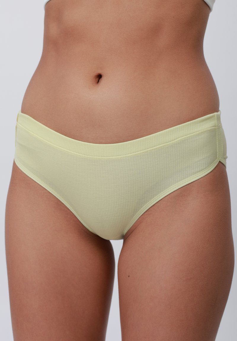Culotte en tissu jaune clair à côtes avec une taille solide, présentant une texture lisse et des côtés sans couture pour plus de confort et un bon ajustement.