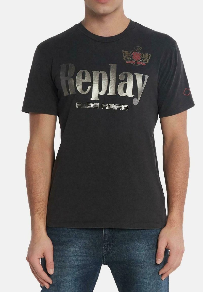 Camiseta negra de cuello redondo hecha de algodón con texto metálico plateado "Replay" y un acento de escudo rojo. Mangas cortas y un corte relajado.
