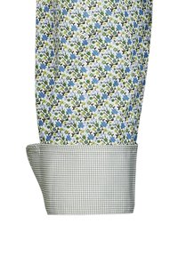 Fondo bianco con motivi floreali blu e verdi sul polsino della camicia floreale. Il polsino a contrasto presenta un motivo a piccoli quadretti grigi.