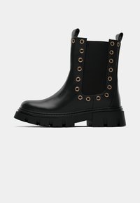 Botín negro de tobillo hecho de cuero suave con paneles laterales elásticos, ojales en tono dorado, suela texturizada gruesa y tira para facilitar el calzado.