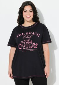 Camiseta negra de manga corta, con bordes cosidos en rosa y un gráfico de cócteles, con el texto "THE BEACH Club", de corte casual.