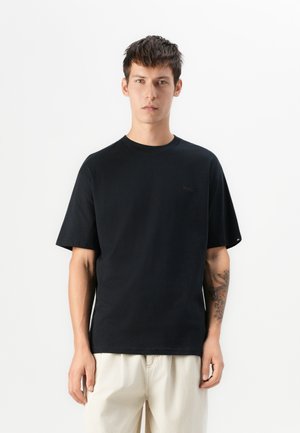 Black cotton t-shirt with a round neckline and short sleeves, featuring a subtle logo on the chest and a relaxed fit.