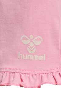 Rosa bomull T-shirt med volangkant, med en ljusfärgad Hummel-logotyp och abstrakt design i mitten. Mjuk, texturerad tyg.
