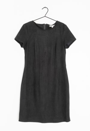 Robe noire courte à manches courtes, longueur genou, avec un col rond, suspendue sur un cintre noir devant un fond blanc.