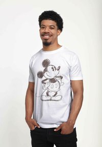 Hvid bomulds t-shirt med en skitseret Mickey Mouse grafik i sort. Kortærmet og med rund hals. Glat tekstur.
