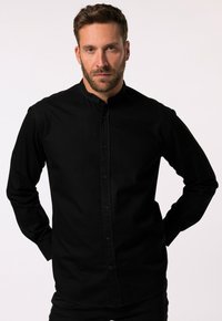 Camicia nera con colletto alla cinese, con maniche lunghe e un tessuto liscio e resistente. Senza motivi o decorazioni visibili.