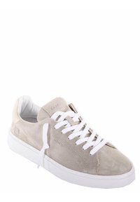Sneaker in suede beige con lacci bianchi e una superficie texturizzata. Presenta una suola in gomma bianca e un design cucito sulla tomaia.