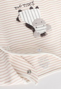 Beige and white striped baby clothing with a stitched zebra patch and snap buttons on soft fabric.