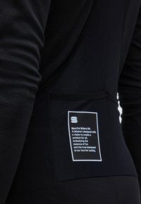 Gros plan sur une poche de cuissard de cyclisme noir avec un texte blanc imprimé concernant le Sportful Riders Kit et la passion du cyclisme.