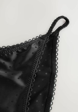 Svart satinlingerie med prickigt mönster, spetsdetaljer längs kanterna och justerbara band för perfekt passform. Slät textur och känsliga designinslag.