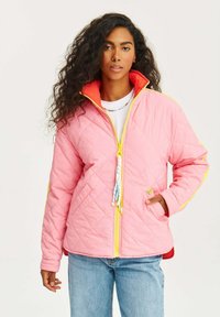 Prošívaná růžová bunda s žlutými akcenty a červenou podšívkou. Má vysoký límec, zip a ozdobné stahovací jezdce.